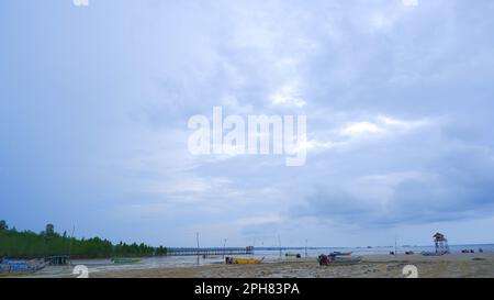 Natürliche Landschaft des Blaugrauen Himmels mit weitläufigen Sandstränden und grünem Wald im Dorf Belo Laut am Nachmittag Stockfoto