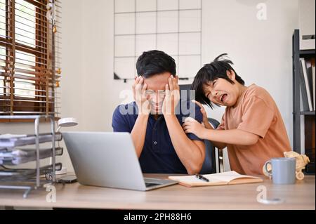 Wütender, unglücklicher und emotional nicht verfügbarer asiatischer Vater ist müde von seinem Sohn und ärgert sich über seinen wütenden kleinen Sohn, während er in h von zu Hause aus arbeitet Stockfoto