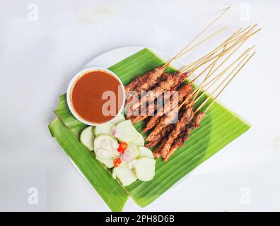 Hähnchen Satay oder Hähnchen Satay serviert mit Longtong, Reiskuchen und Erdnusssoße. Serviert auf Bananenurlaub Stockfoto