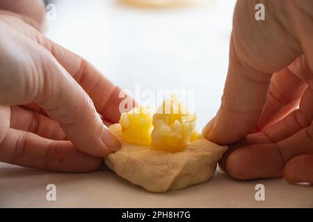 Der Prozess der Herstellung von Kuchen mit Kartoffeln zu Hause in der Küche auf einem weißen Tisch, hausgemachte Gewohnheiten mit Kartoffeln Stockfoto