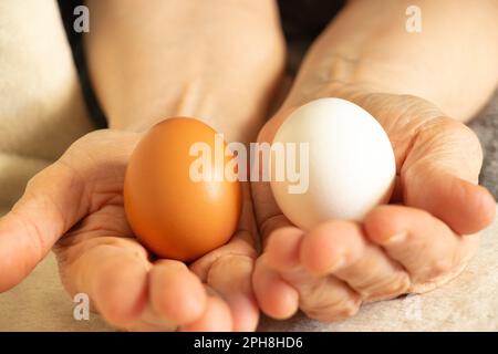 Zwei Hühnereier in den Händen einer alten Frau, Hühnereier schließen sich Stockfoto