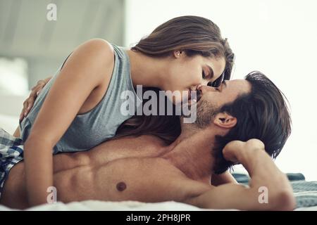 Ich bin noch nicht fertig damit, dich zu küssen. Ein liebevolles junges Paar, das intim im Bett liegt. Stockfoto