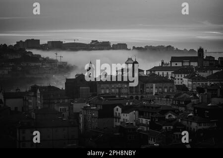 Blick auf die Altstadt bei Abenddämmerung im Nebel, Porto, Portugal. Schwarzweißfoto. Stockfoto