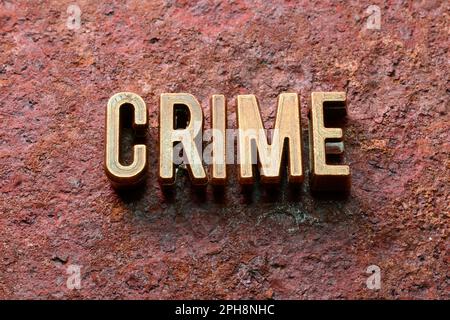 Ein Verbrecherwort aus Metallicbuchstaben auf rostiger Oberfläche Stockfoto