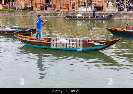 Ein junger vietnamesischer junger Mann rudert in einem kleinen Boot auf dem Fluss Thu Bon in Hoi an, Vietnam. Stockfoto