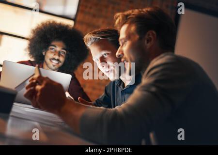 Überstunden sind unvermeidbar. Eine Gruppe von Designern, die ein Brainstorming im Sitzungssaal durchführen. Stockfoto