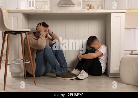 Vater und sein Sohn versteckten sich während des Erdbebens unter dem Tisch in der Küche Stockfoto