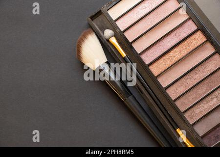 Mehrfarbige Augenschatten für Make-up und Pinsel auf dunklem Hintergrund, Schönheitsschminke Stockfoto