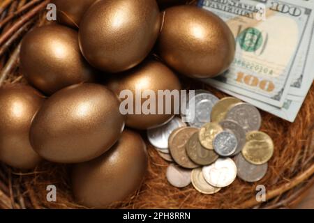 Goldene Eier und Geld im Nest, über der Aussicht. Pensionskonzept Stockfoto