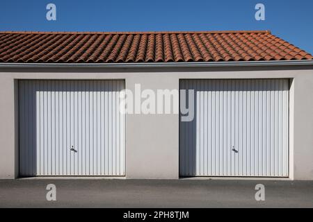 Garage mit Doppelbereich, zweitüriger weißer Autoeingang an einem privaten Haus mit Fassade Stockfoto