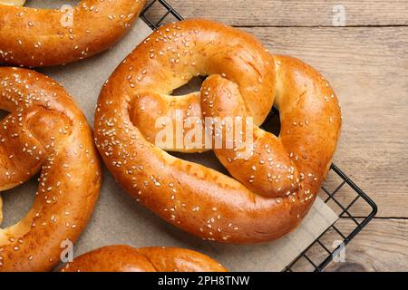 Kühlregal mit leckeren frisch gebackenen Brezeln auf Holztisch, Draufsicht Stockfoto