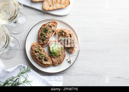 Scheiben Brot mit köstlicher Pastete, serviert auf einem weißen Holztisch, flach liegend. Platz für Text Stockfoto