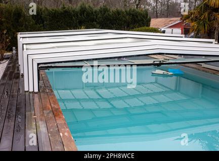 Swimmingpool mit offenem Schiebedeckel aus Polycarbonat Stockfoto