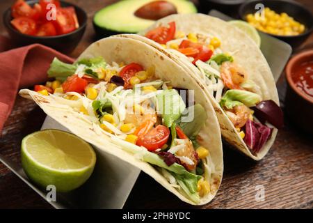 Köstliche Tacos mit Garnelen, Käse und Limette auf einem Holztisch, Nahaufnahme Stockfoto