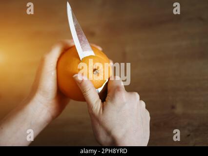 Weibliche Hände schälen orangefarbenes Messer. Gesunde Ernährung Stockfoto