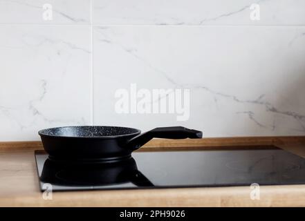 Bratpfanne auf modernem, schwarzem Induktionsherd, Herd, Herd oder eingebautem Herd mit Keramikplatte im Küchenbereich Stockfoto