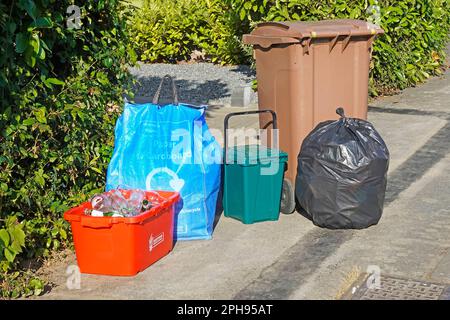 Getrennte Müllabfuhr wöchentliche Sammlung durch den rat Rotglasbehälter blauer Papierkartensack grüner Lebensmittelbehälter braun Wheelie Garten schwarz nicht recycelbar Stockfoto