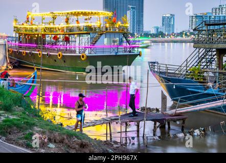 Phnom Penh, Kambodscha-Dezember 23. 2022: Mitarbeiter der Bootstour auf dem Fluss warten darauf, dass weitere Passagiere an Bord gehen, bevor sie zu einer farbenfrohen abendlichen Tour durch die Stadt aufbrechen Stockfoto