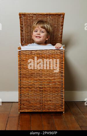 Der glückliche Junge spielt Verstecken und guckt aus einer Kiste Stockfoto