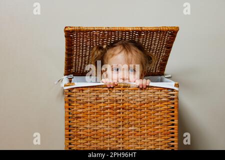Nahporträt eines Mädchens, das Verstecken in einer Wäschekiste spielt Stockfoto