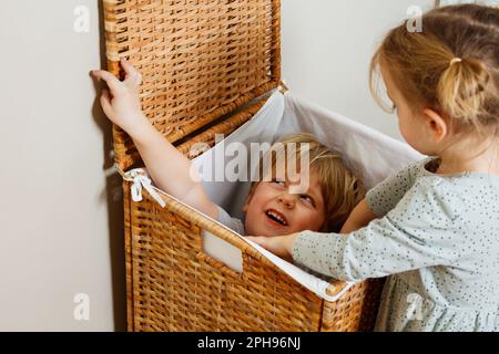 Zwei Kinder verstecken sich im Holzwäschekasten Stockfoto