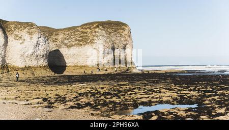 Flamborough Head Strand. North Landing Beach - wunderschöner Sand, weiße Kiesel und Felsenbecken. Touristen-Silhouetten. Hochwertiges Foto Stockfoto