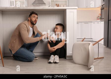 Vater und sein Sohn versteckten sich während des Erdbebens unter dem Tisch in der Küche Stockfoto