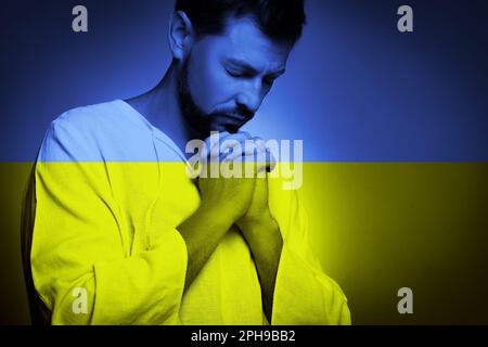 Bete für die Ukraine. Doppelte Exposition von betenden Menschen und ukrainischer Nationalflagge Stockfoto