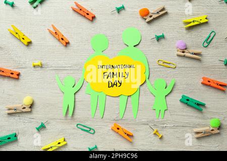Alles Gute Zum Familientag. Flachliegenkomposition mit Papierfiguren von Eltern und ihren Kindern auf Holzhintergrund Stockfoto
