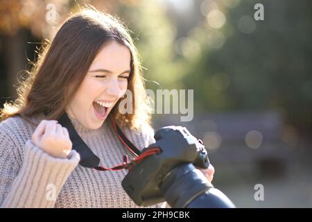 Aufgeregter Fotograf, der Fotos überprüft, um den Erfolg im Winter mit der Kamera zu feiern Stockfoto