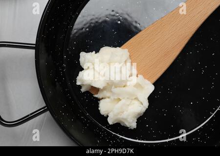 Bratpfanne mit Kokosöl und Holzspachtel auf hellgrauem Tisch, Draufsicht Stockfoto