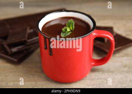 Tasse mit köstlicher heißer Schokolade mit frischen Minzblättern auf einem Holztisch Stockfoto