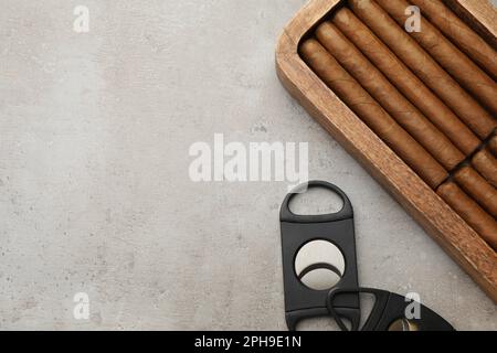 Box mit Zigarren und Schneidezähnen auf hellgrauem Tisch, flach liegend. Platz für Text Stockfoto