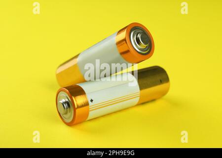 Zwei neue AA-Batterien auf gelbem Hintergrund, Nahaufnahme Stockfoto