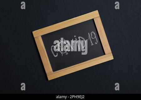 Tafel mit Wort Covid19 auf schwarzem Hintergrund, Draufsicht Stockfoto
