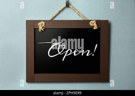 Kleine Kreidetafel mit Wort Offen an hellblauer Wand Stockfoto