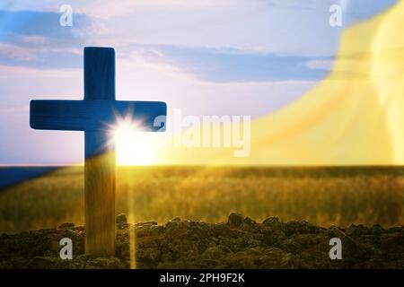 Bete für die Ukraine. Doppelte Exposition von Kreuzen im Freien und ukrainische Flagge Stockfoto