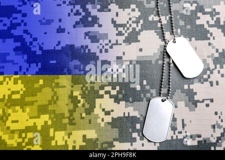 Doppelte Belichtung der ukrainischen Flagge und militärischer ID-Tags auf Tarnstoff Stockfoto