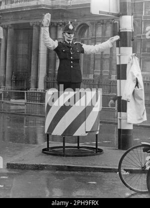 Ein Polizist, der an einem feuchten Tag den Verkehr in Queens Gardens, Kingston upon Hull, East Yorkshire, England, UK, ca.1960, leitet. Diese Rolle wird oft als Punktaufgabe bezeichnet. Er steht auf einer erhöhten, kreisförmigen Plattform und verwendet Handzeichen, um dem Straßenverkehr und Fußgängern anzuzeigen, ob sie anhalten oder weiterfahren – ein altes 1950er/60s-Foto. Stockfoto