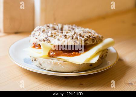 Köstliche süße Marmelade und Käsesandwich auf Bagelbrot. Ein Bagel ist ein Brot, das traditionell aus Weizenmehl hergestellt wird und normalerweise ein Loch in der Mitte hat. Stockfoto