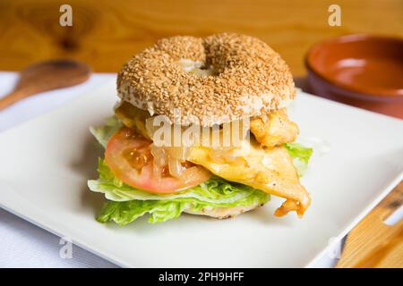 Köstliches Hühnchen-Sandwich auf Bagelbrot. Ein Bagel ist ein Brot, das traditionell aus Weizenmehl hergestellt wird und normalerweise ein Loch in der Mitte hat. Stockfoto