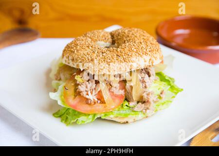 Köstliches Thunfischsandwich auf Bagelbrot. Ein Bagel ist ein Brot, das traditionell aus Weizenmehl hergestellt wird und normalerweise ein Loch in der Mitte hat. Stockfoto