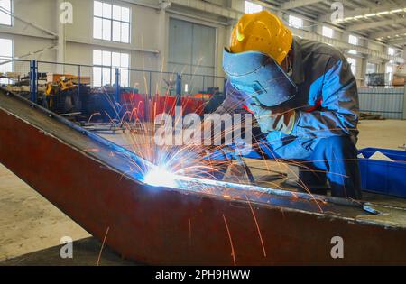 LIANYUNGANG, CHINA - 27. MÄRZ 2023 - Ein Arbeiter montiert Teile eines Hydraulikbaggers in einer Produktionswerkstatt von Luyou Heavy Industry Co LTD in Lianyungang, Stockfoto