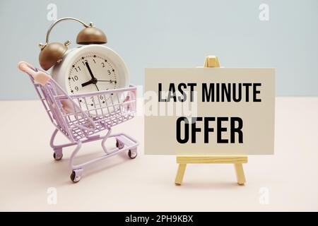 Last-Minute-Angebot Textnachricht für Promotion mit Wecker und Einkaufswagen auf pinkfarbenem und blauem Hintergrund Stockfoto