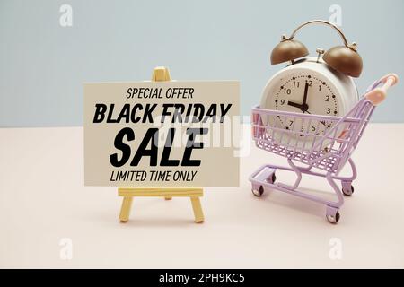 Black Friday Sale Textnachricht für Werbeaktion mit Wecker und Einkaufswagen auf pinkfarbenem und blauem Hintergrund Stockfoto