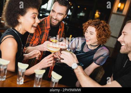 Fröhliche, multiethnische Leute, die verschiedene Cocktails in der Nähe von Tequila-Shots in der Bar, Stock Image Stockfoto