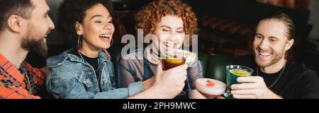 Positive, multiethnische Leute, die verschiedene Cocktails halten, während sie in der Bar, Banner, Stock Image klappern Stockfoto