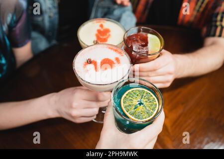 Kurze Aussicht auf Freunde, die mit verschiedenen kalten Cocktails in der Bar klappern, Stockbild Stockfoto