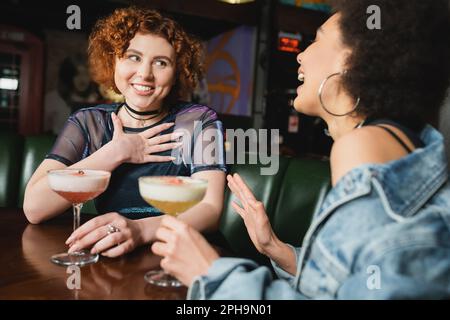Multiethnische Freundinnen, die Spaß haben, während sie kalte Schaumcocktails in der Bar reden, Stock Image Stockfoto