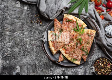 Pizzaschneiden mit Marihuana-Blättern in einer Metallschüssel auf dunklem Holzhintergrund Stockfoto